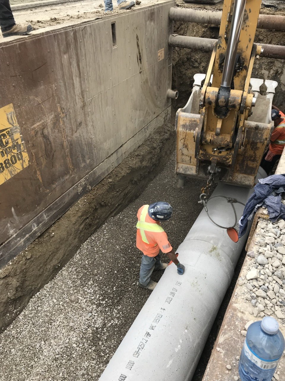 Worker in deep trench with pipe